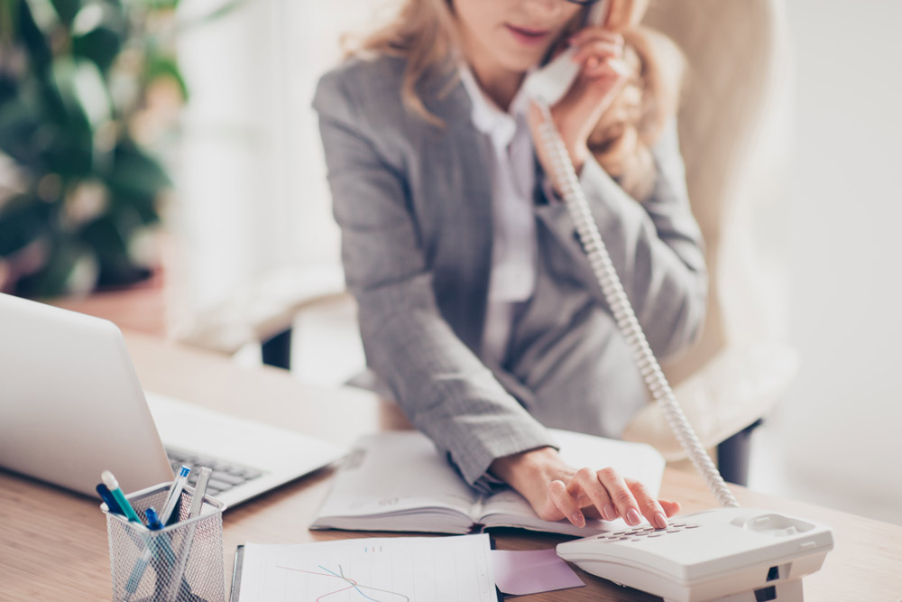Frau im Anzug wählt eine Nummer am Telefon